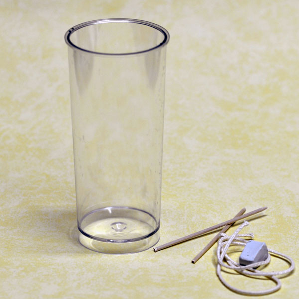 Transparente runde Kerzen-Gießform für Stumpenkerzen 55x140mm mit beiliegendem Docht, Fixierstab und Knetmasse auf weißem Hintergrund.